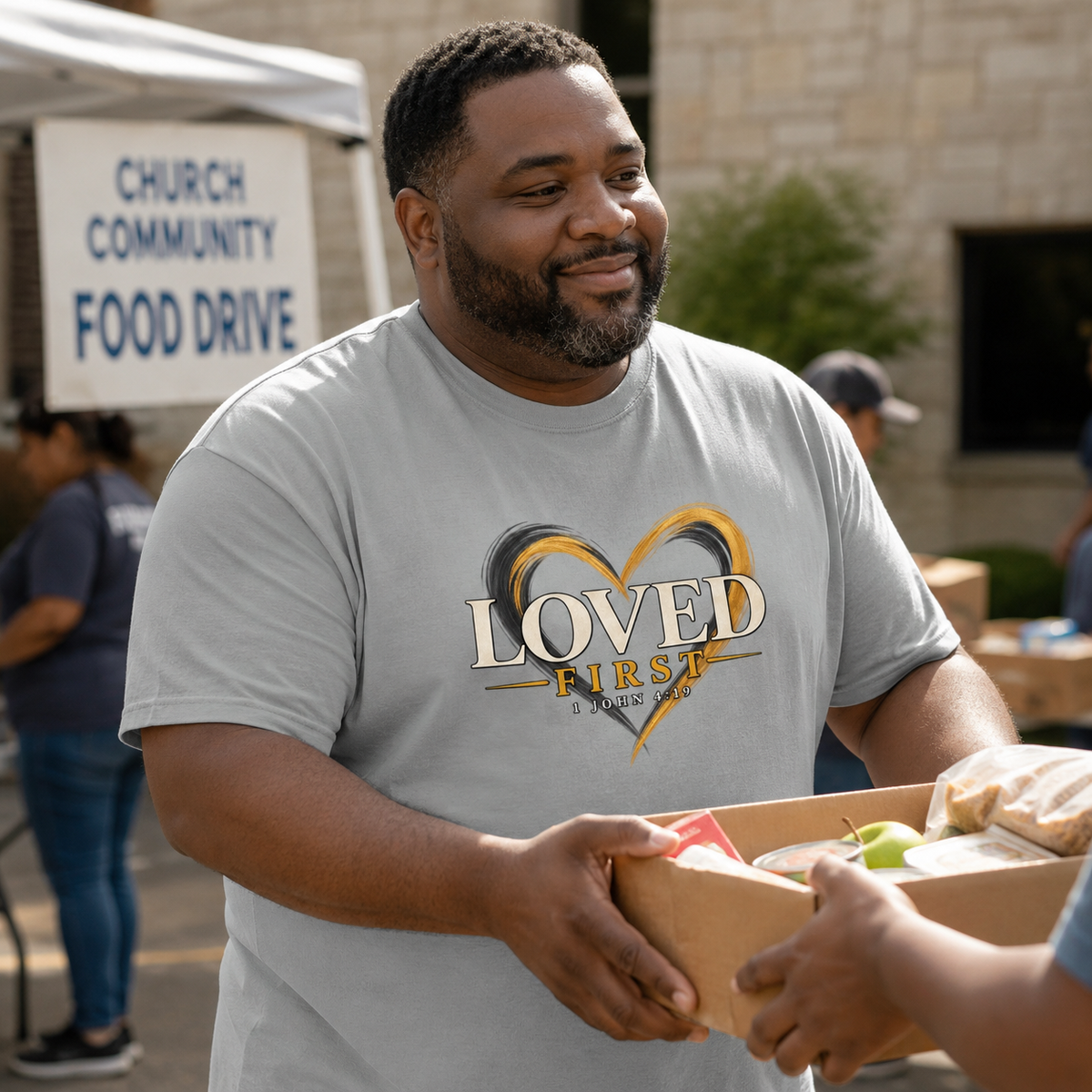 Man wearing the He First Loved Us shirt while serving at a community food drive