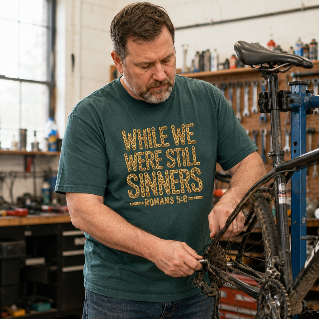 Man wearing While We Were Still Sinners Romans 5:8 Christian T-shirt at a bicycle workshop