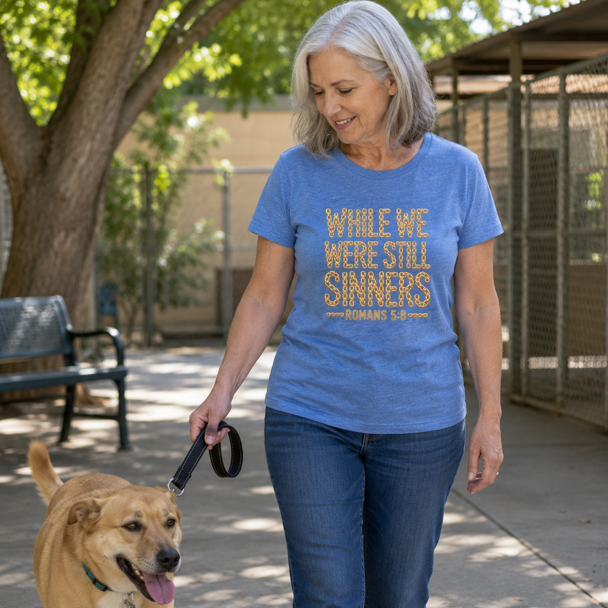 Woman wearing While We Were Still Sinners Romans 5:8 Christian T-shirt while walking a rescue dog